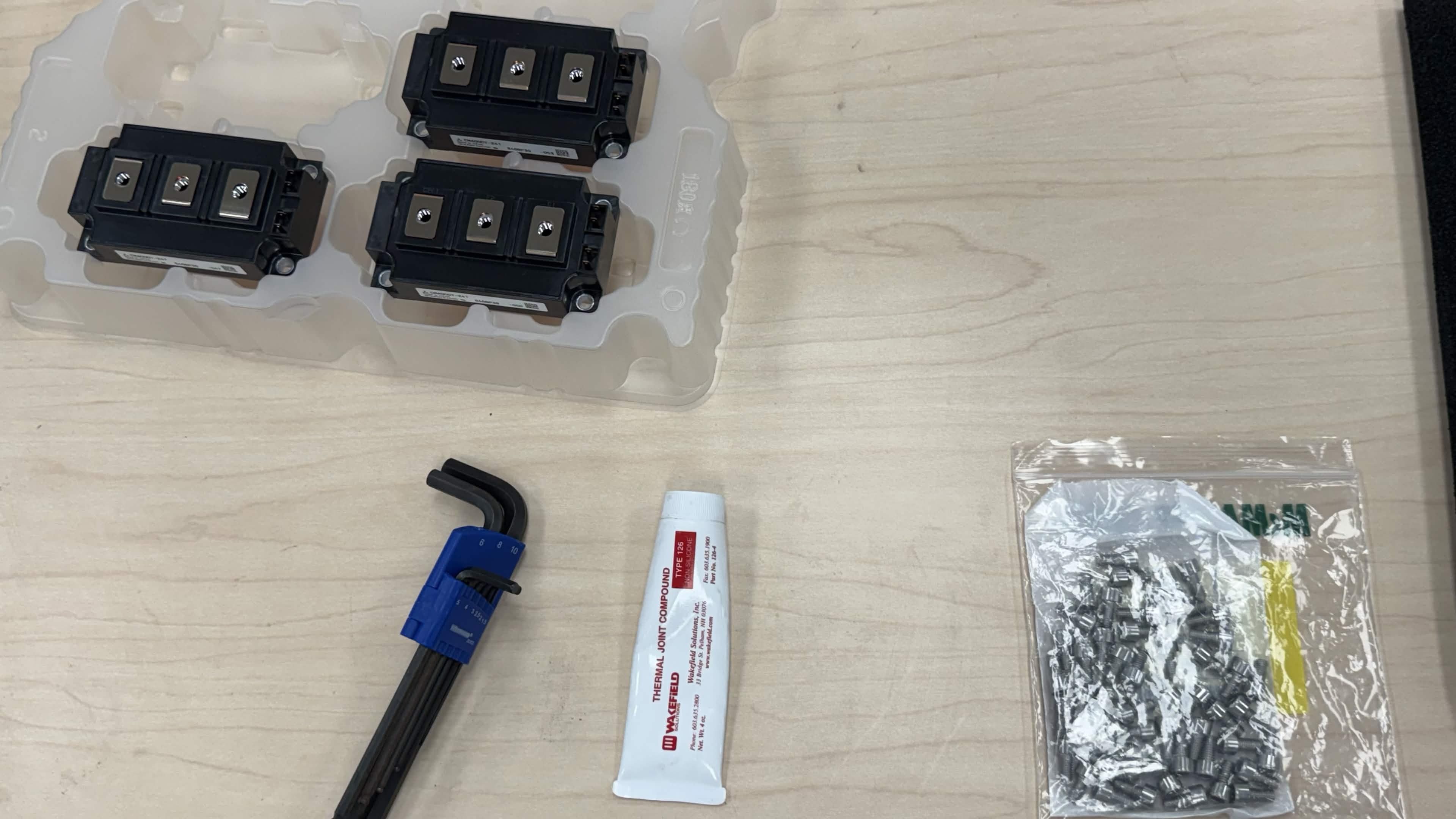 Close-up of thermal paste, screws, hex keys, and IGBT modules