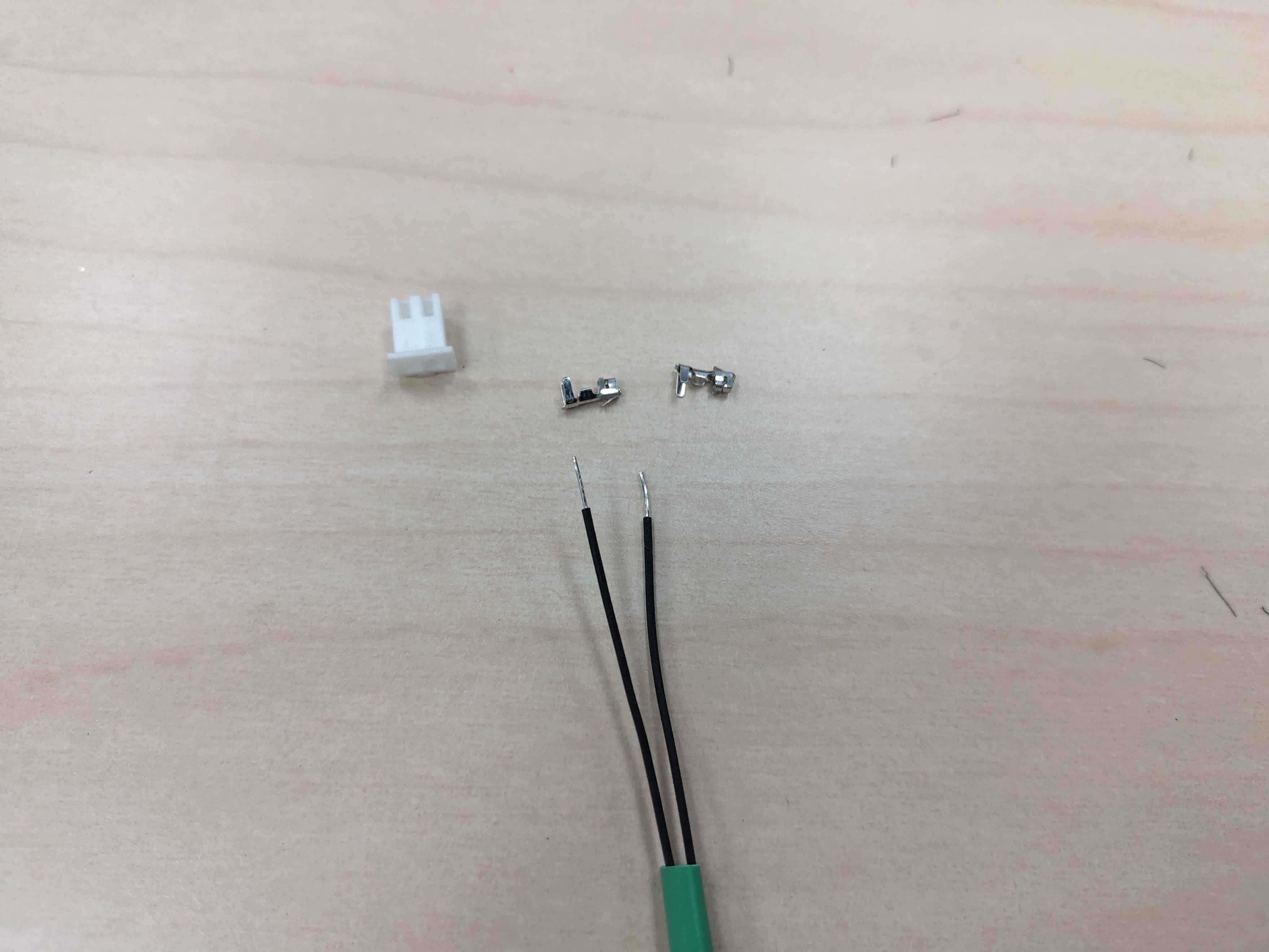 Stripped wire ends, terminals, and housing laid out for crimping